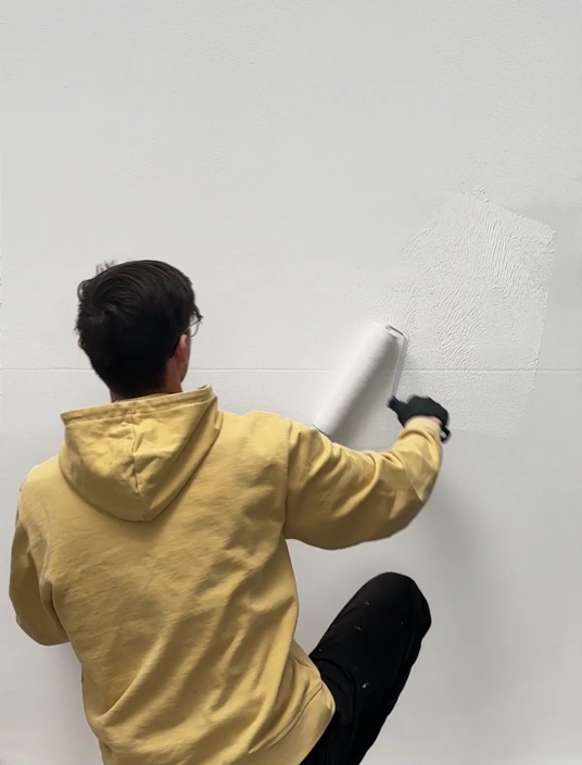 Applying Papirus Primer to a wall with a roller before cotton plaster